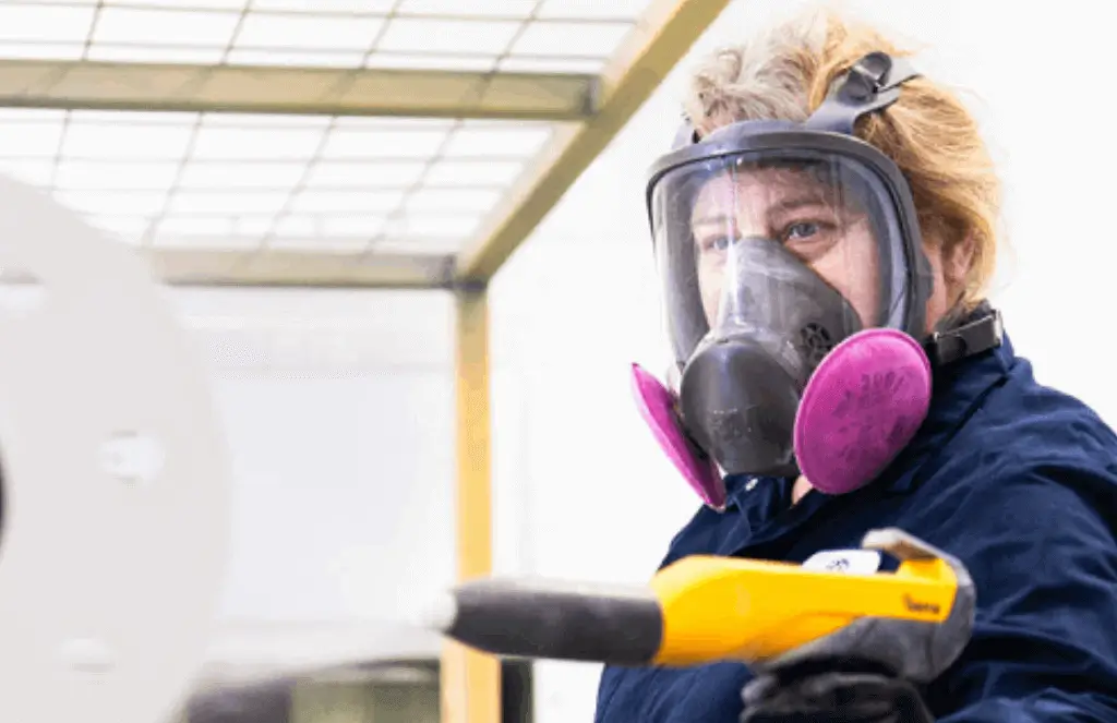 Application de peinture en poudre sur une pièce métallique en atelier