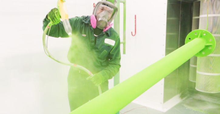 Technicien appliquant une peinture électrostatique verte sur une pièce métallique